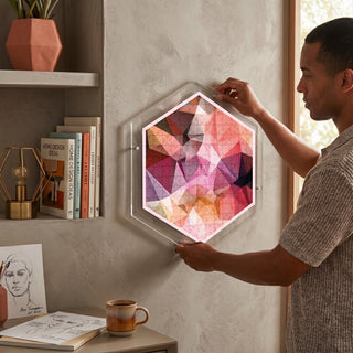 Person hanging the Prism Light acrylic wall art puzzle on a living room wall