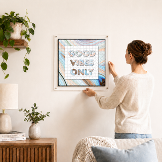 Person hanging the Good Vibes Only acrylic wall art puzzle on a living room wall