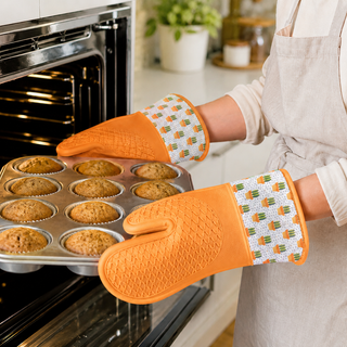Terracotta silicone oven mitts holding a hot baking tray from the oven